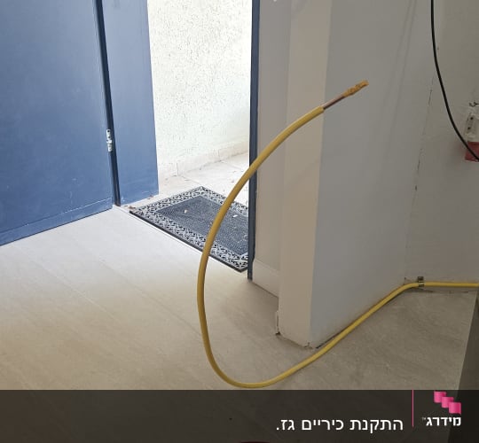 צינור גז צהוב מחובר לקיר ליד דלת פתוחה